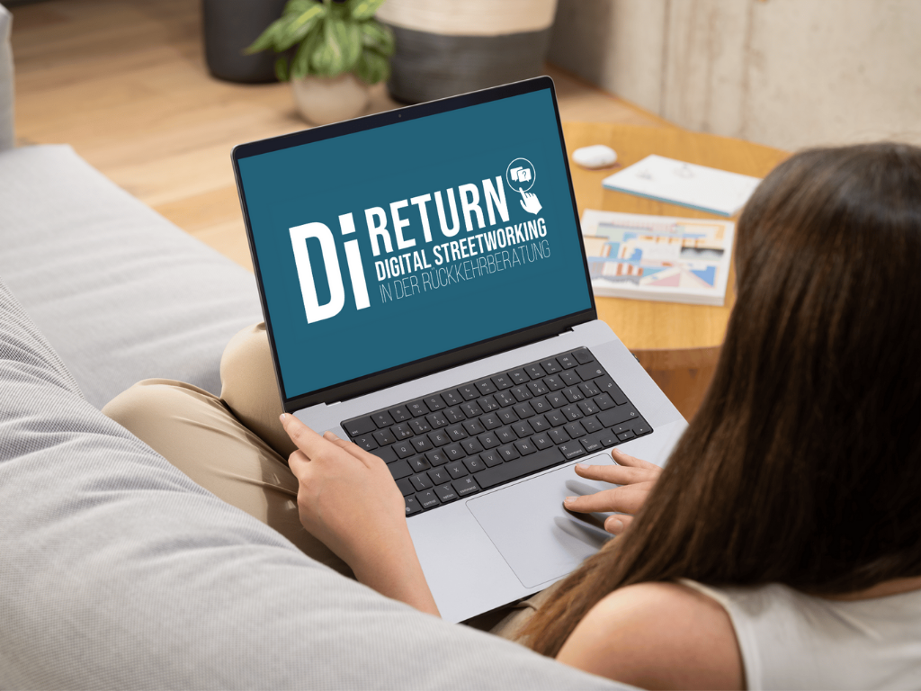 Eine Person sitzt auf einer Couch und benutzt einen Laptop, auf dem der Text DiReturn Digital Streetworking in der Rückkehrberatung angezeigt wird.